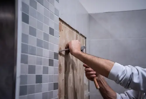 A bathroom remodeling project getting started by pulling the tile from the shower wall.