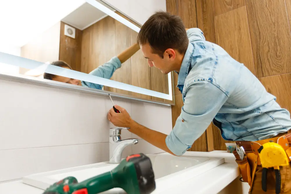 Contractor from Top Builders installing a mirror during a bathroom remodel in Wheat Ridge.