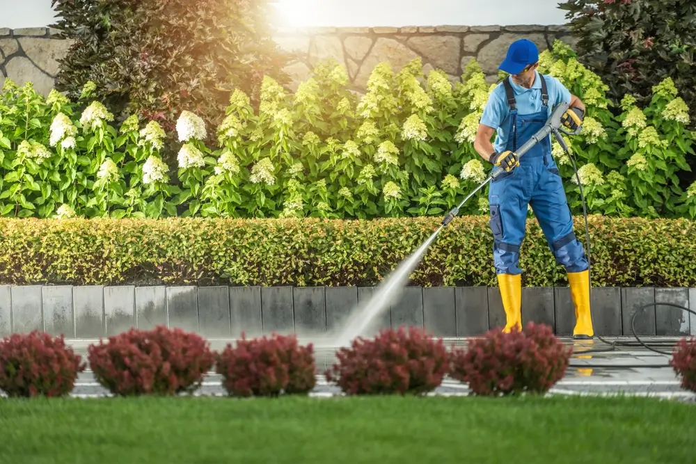 Professional pressure washing a concrete driveway as part of routine maintenance in Arvada